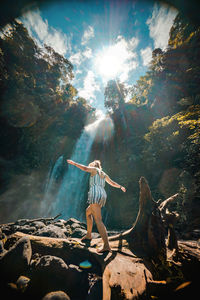 Young woman with arms raised on rock