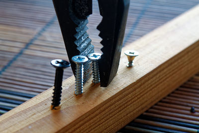 Close-up of pliers and screw on wood