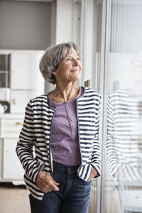 Portrait of confident senior woman looking through window