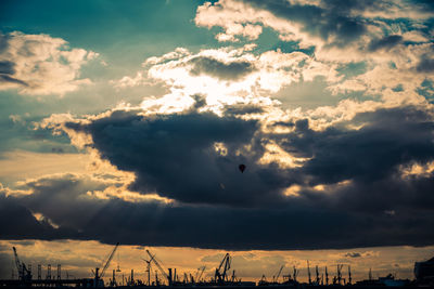 Low angle view of silhouette cranes against sky during sunset