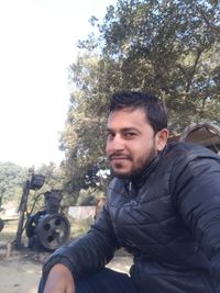 Portrait of young man photographing against trees