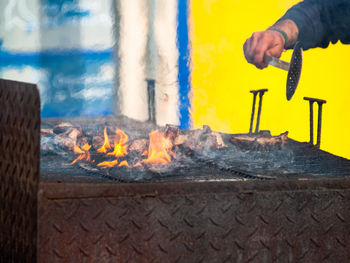 Midsection of man with fire on barbecue grill