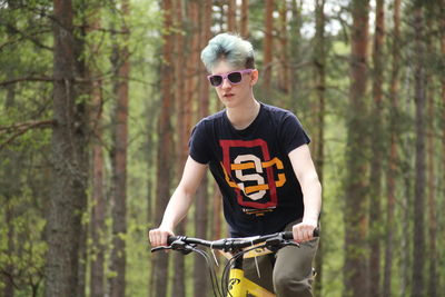 Young man riding bicycle in forest