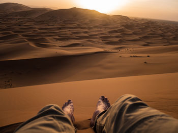 Low section of man sitting on desert