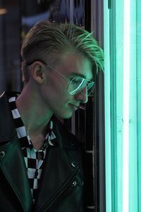 Young man looking through illuminated window