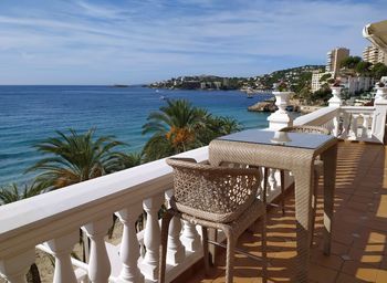 Chairs and table by swimming pool at beach against sky