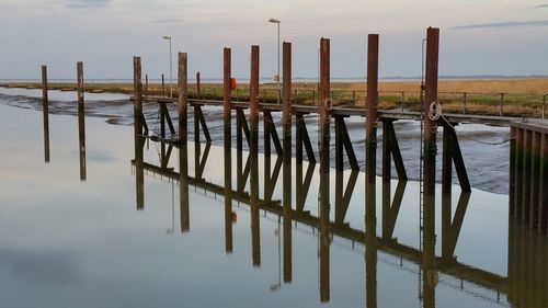 Wooden posts in sea against sky