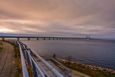 Bridge over river against sky at sunset