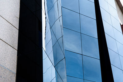 Low angle view of glass building against sky