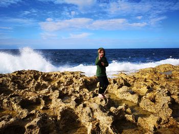 Full length of man on rock at beach against sky