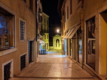 Empty alley amidst buildings at night