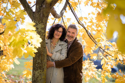 Portrait of a mature couple 50 years old in an autumn park embracing and looking at the camera