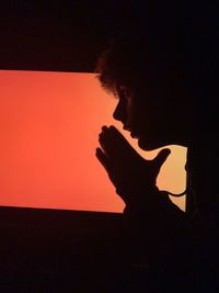 Portrait of silhouette woman standing against orange sky