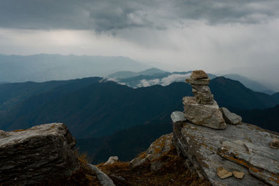 Stack of rocks on mountain against cloudy sky