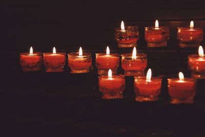 Illuminated tea light candles in darkroom