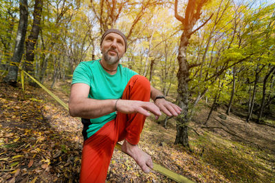 Portrait of a mature man in a scarf on his head sits on a taut slackline 