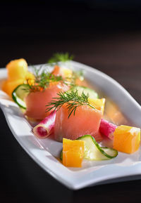 Buffet serving of pickled salmon slices with radish, cucumber and orange cubes