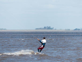 Man surfing in sea against sky