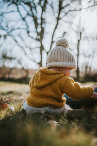 Rear view of baby girl wearing warm clothing while sitting on land