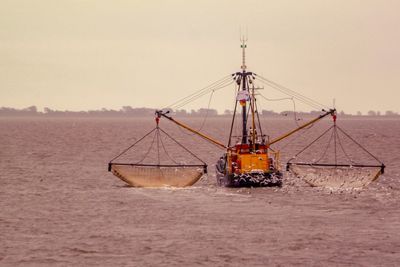 Fishingboat in sea against clear sky