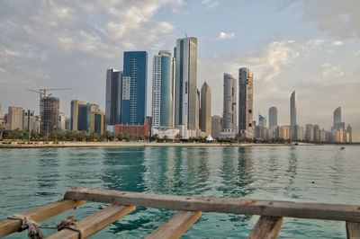 Modern buildings by river against sky in city