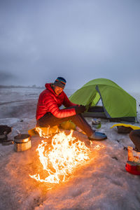 Mountaineer enjoys campfire while camping on a glacier, baffin island