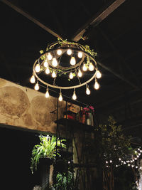 Low angle view of illuminated lighting equipment hanging at night