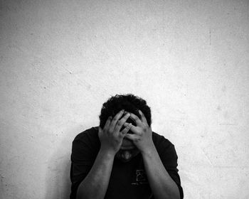 Frustrated man sitting against wall