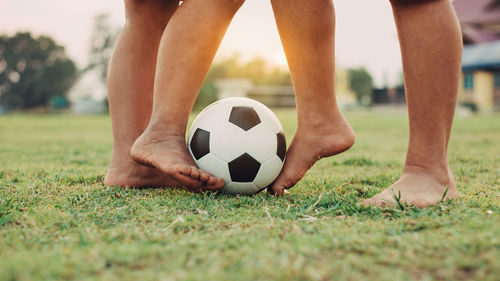 Low section of people playing soccer on field