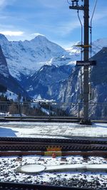 Railroad tracks by snowcapped mountains against sky