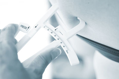 High angle view of woman measuring fats on stomach