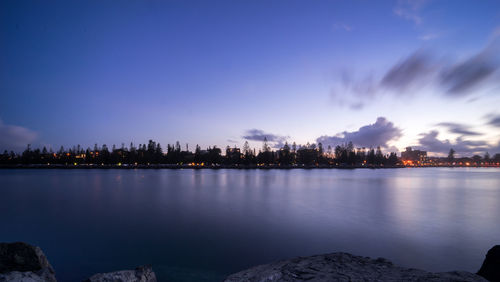 Illuminated city by buildings against sky at dusk