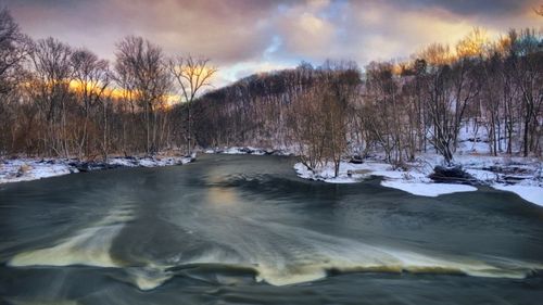 Scenic view of river against cloudy sky during winter