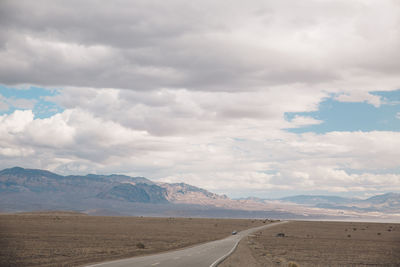 Road by desert against sky