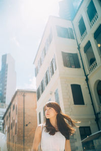 Portrait of woman standing against buildings in city