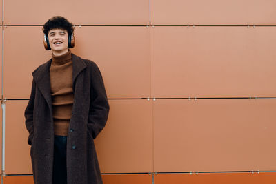 Portrait of young woman standing against wall