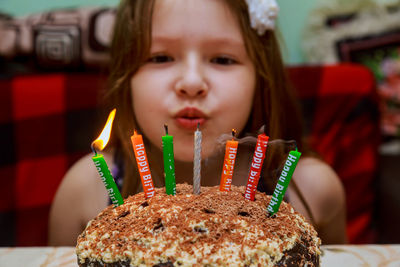 Close-up portrait of smiling girl sitting by cake at home