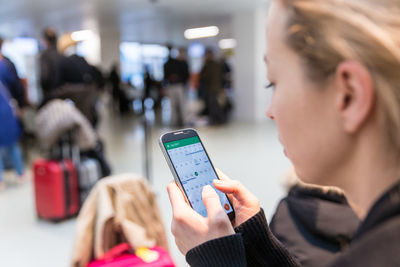 Midsection of woman using mobile phone sitting at airport