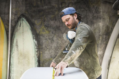 Surfboard shaper measuring a new design