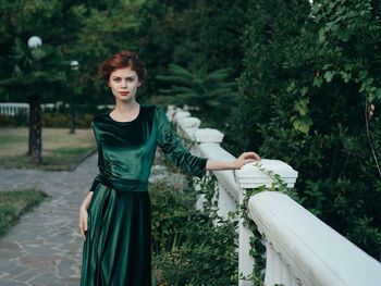 Portrait of young woman standing against plants