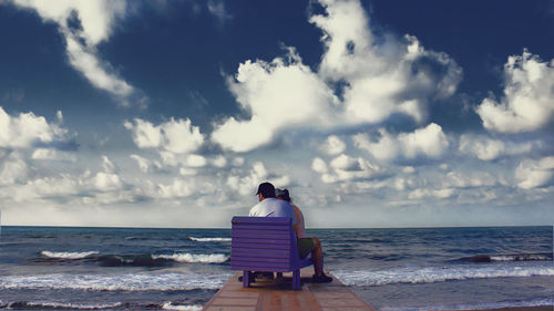 Rear view of people sitting on beach