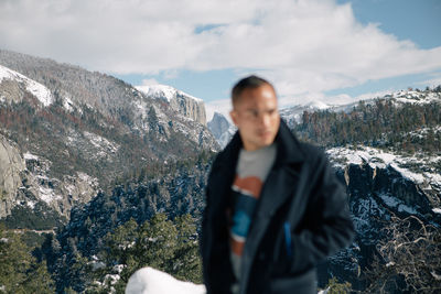 Man standing on rock against sky during winter