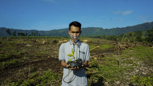 Portrait of young man standing on mountain against sky