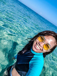 Portrait of smiling young woman wearing sunglasses in sea