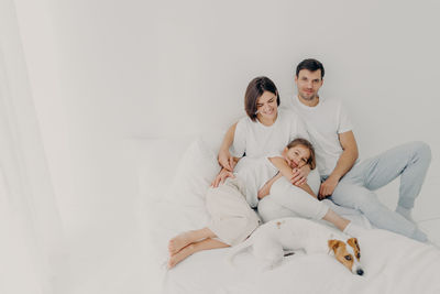 High angle view of cheerful family relaxing on bed with dog at home