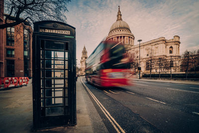 Blurred motion of bus on street against buildings in city