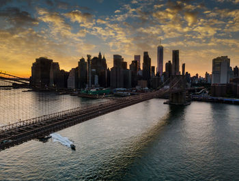 Scenic view of river by buildings against sky during sunset