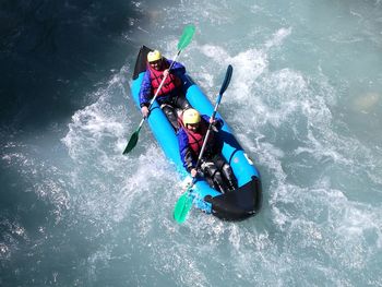 High angle view of friends rafting in river