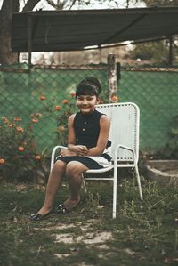 Portrait of cute girl sitting on chair at yard