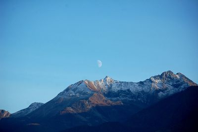 Low angle view of snowcapped mountain against blue sky